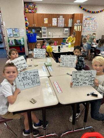 Students pose with the words they wrote on their whiteboards. 