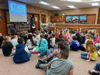 Mrs. Findlay reading aloud to a group of students about courage.