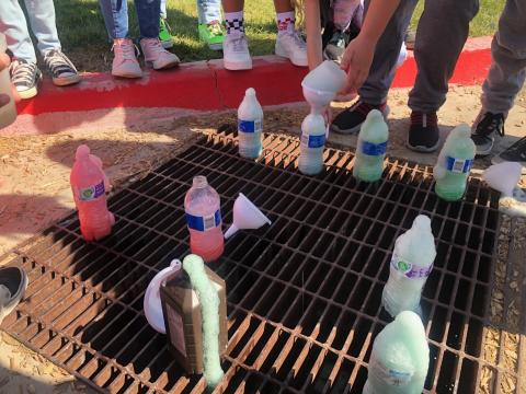 Eight bottles of Elephant Toothpaste sitting on a sewer grate