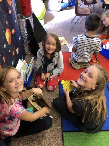 Fourth and first grade buddies reading with a poppet