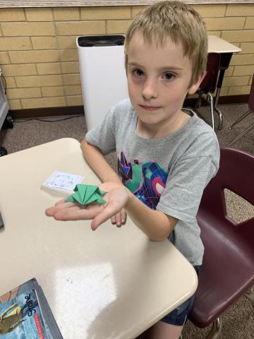 A student shows the origami frog that he made. 