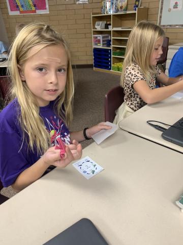 A student shows the origami frog that she made. 