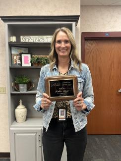 Amber Stone holding her teacher of the year plaque. 